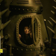 Madam Rouge peeks tentatively out of the time machine's submarine-like hatch.
